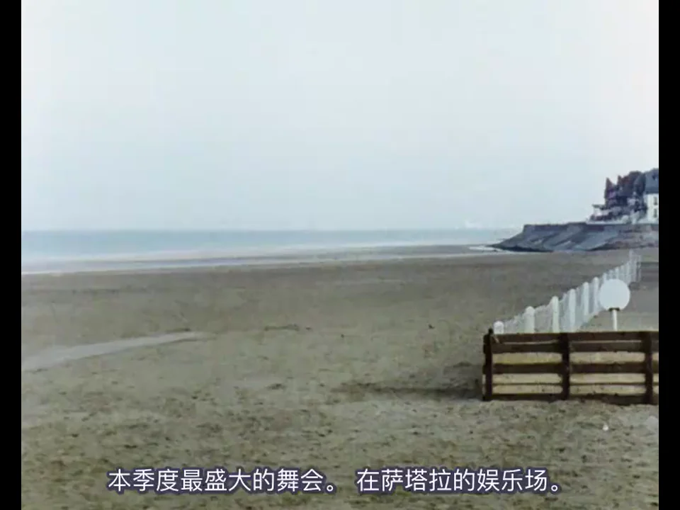 灰白天空下的空海滩、长椅与白色围栏，画面无人，字幕却谈到本季度最大的舞会
