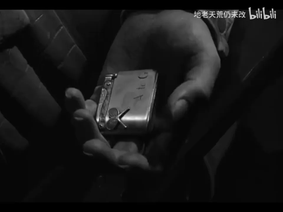 Bruno 张开的手掌占据画面中央,矩形金属打火机横在掌中,正面可见“A to G”和交叉网球拍图案。